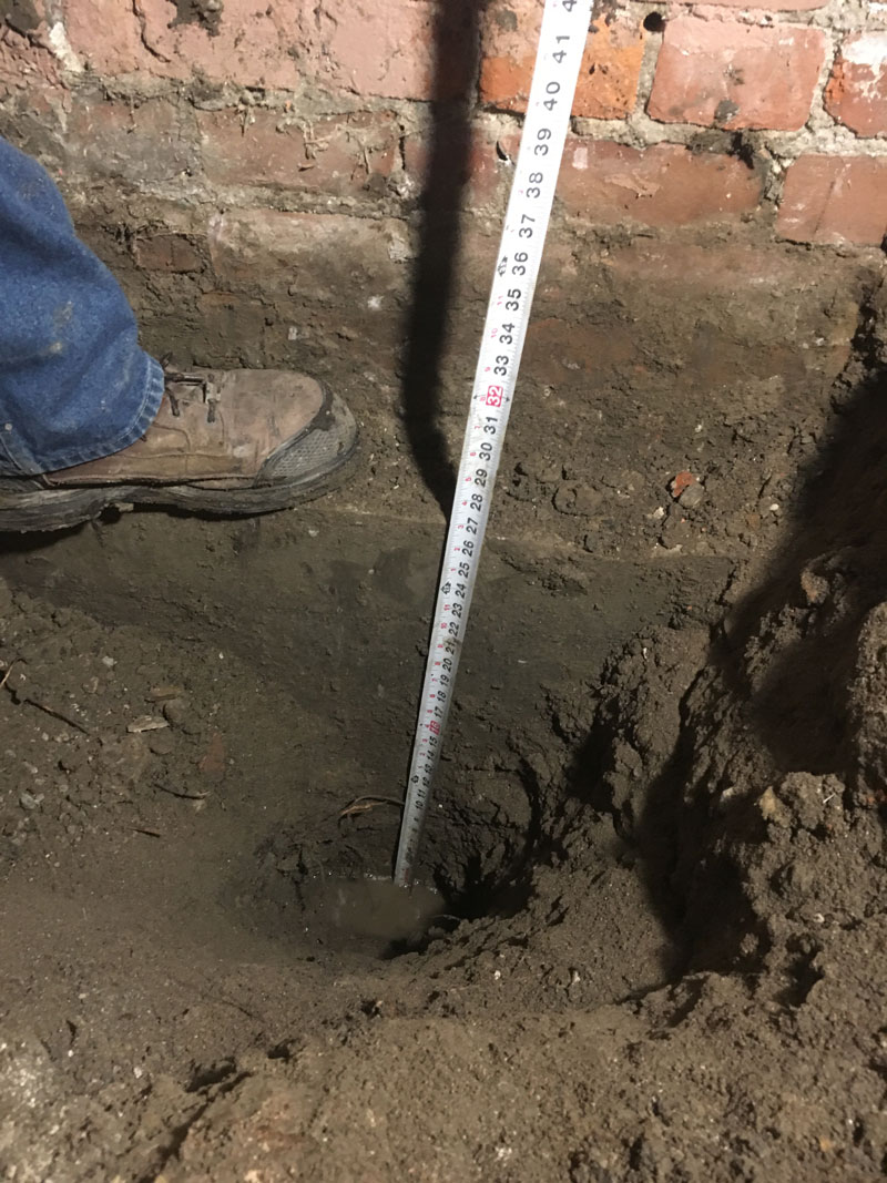 A tape measure inserted into a hole in the floor caused by a flood